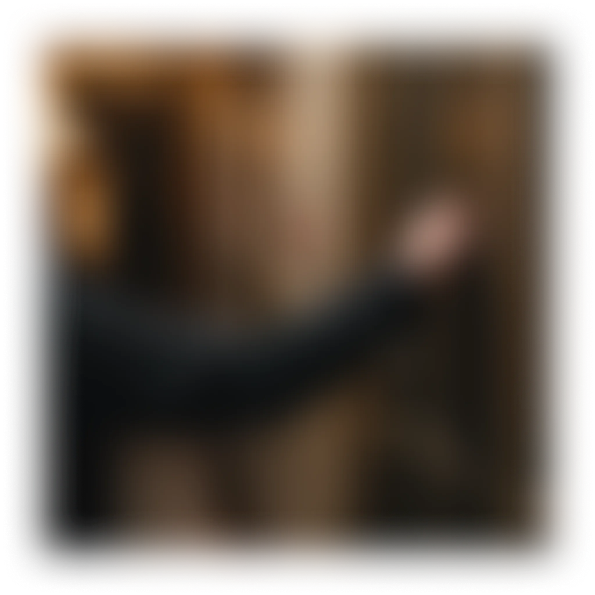 A blurred image showing a dark arm reaching into a brown background.