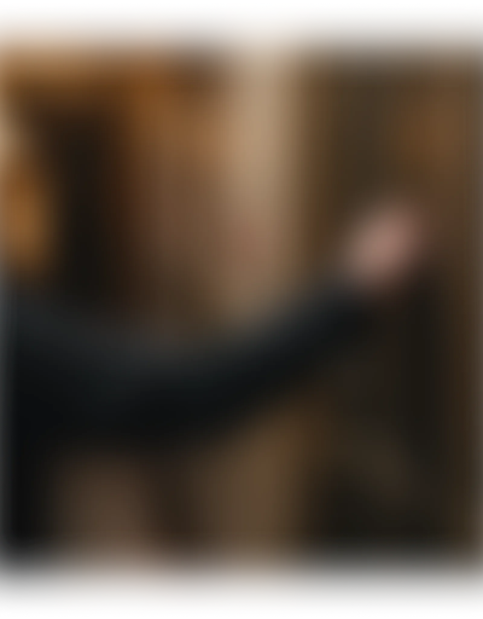 A blurred image showing a dark arm reaching into a brown background.